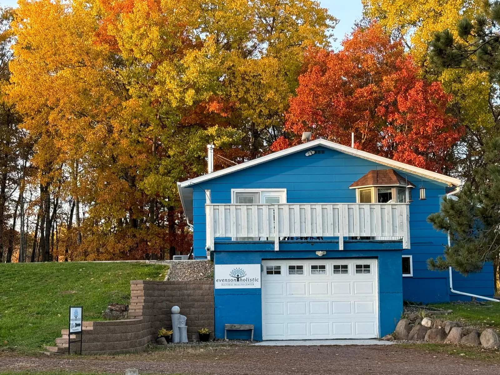 The Evenson Holistic office, a bright blue building under blazing fall maples