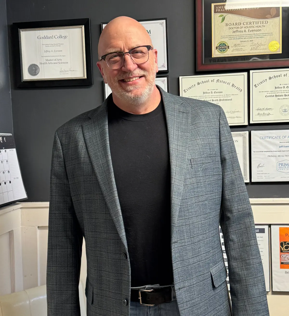 Jeff Evenson in his session room in front of his framed degrees and certifications