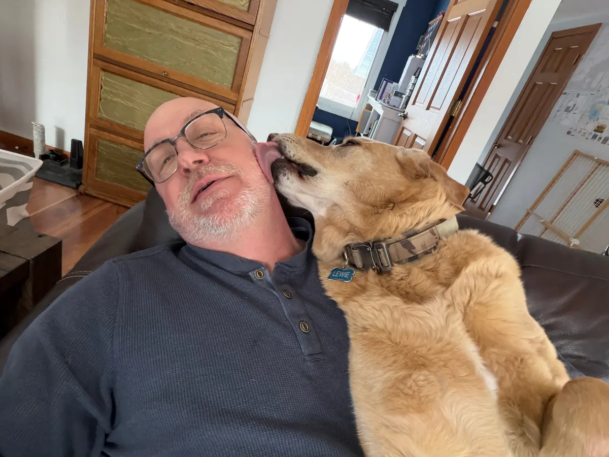 Jeff getting a face full of kisses from his dog, Lewie